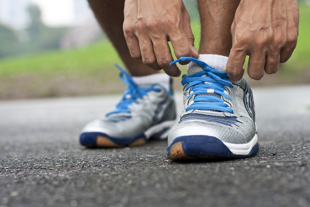 a close up of a runner adjusting their shoes
