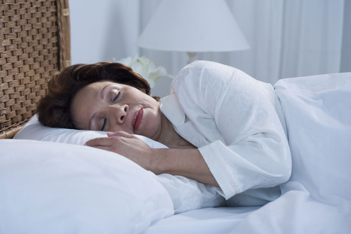 a lady sleeping with her head on a white pillow