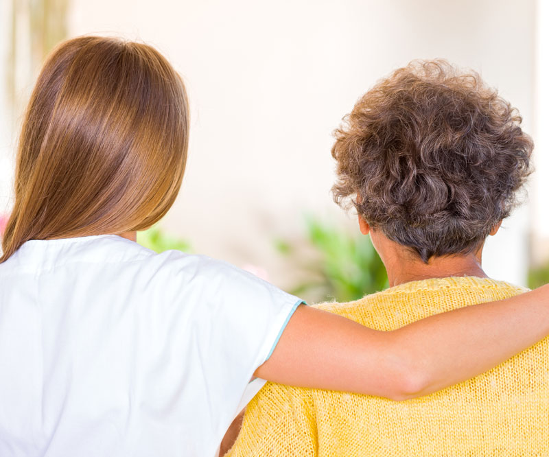 two people with their back to the camera with one person placing an arm around the other