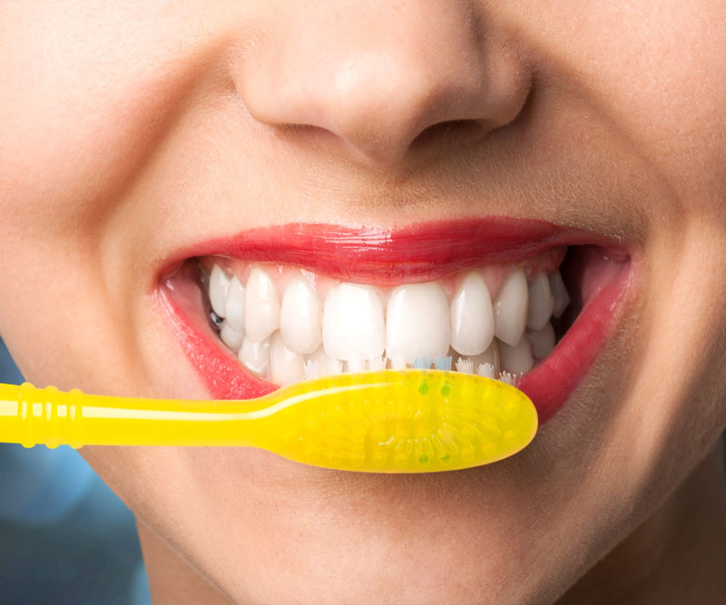 close up of a lady smiling and brushing her teeth