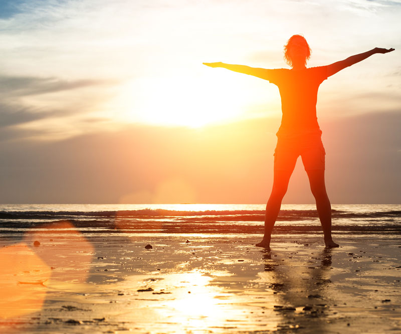 a silhouette of a person standing in prone position on the beach during sunrise