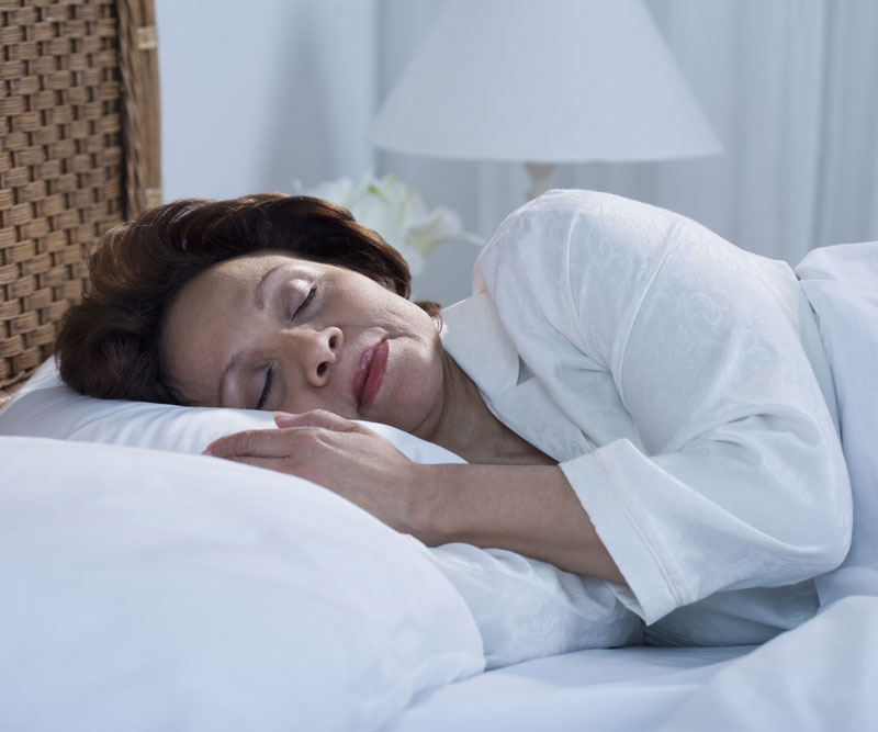 a lady sleeping with her head on a white pillow