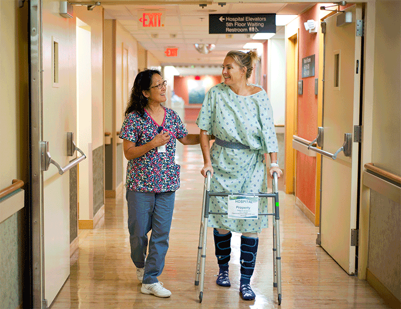 patient and healthcare professional walking down a hallway.