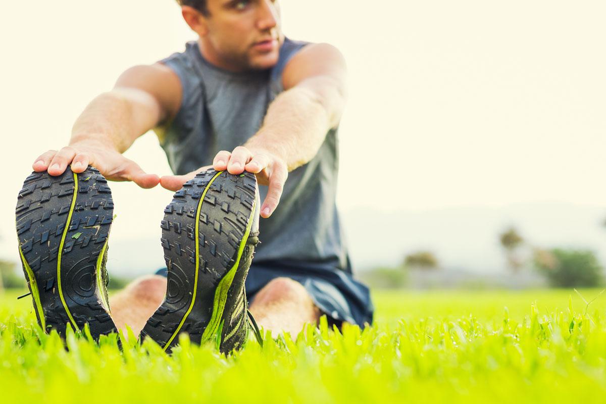 man sitting in the grass stretching