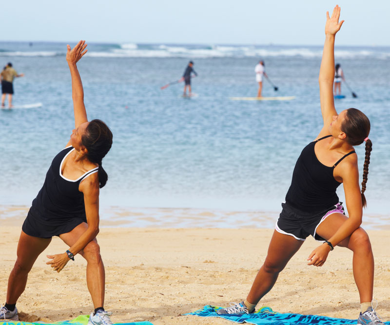 two people on the beach doing yoga