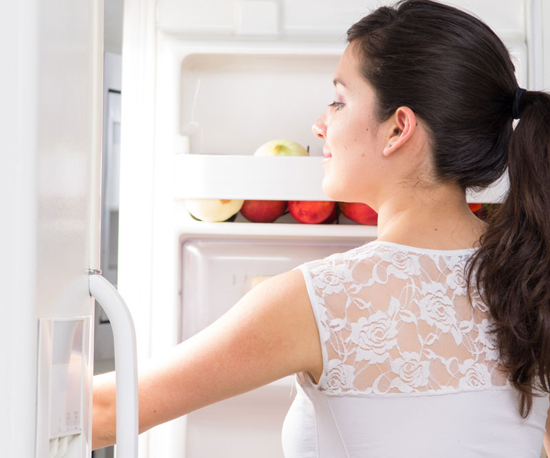 a lady looking inside a refrigerator