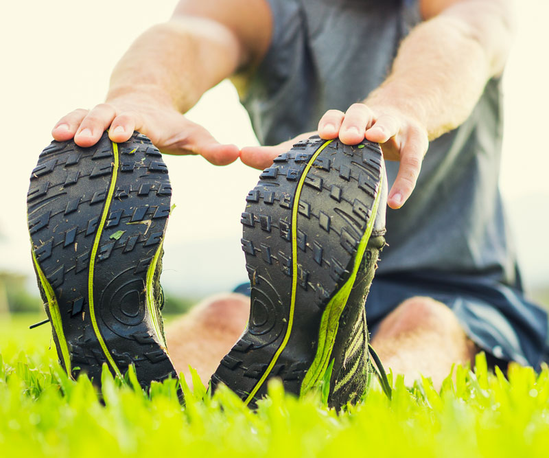 man sitting in the grass stretching