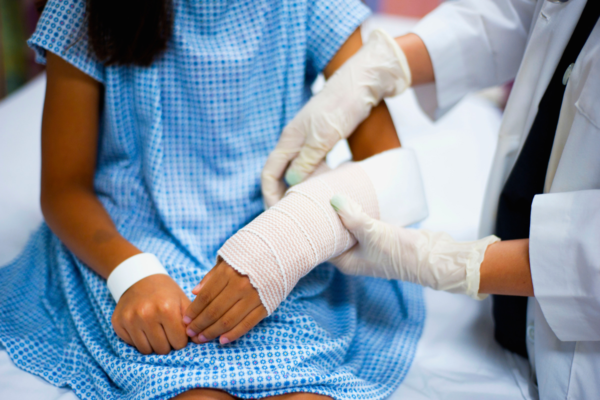 a young girl getting a cast applied by a doctor