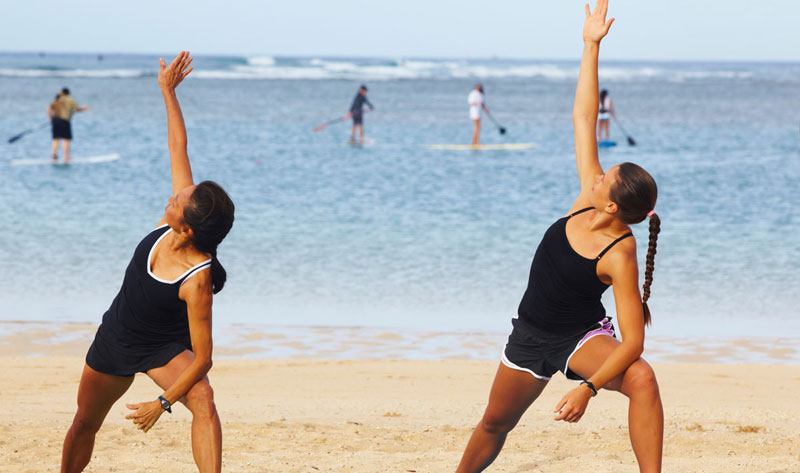 two women working out at beach