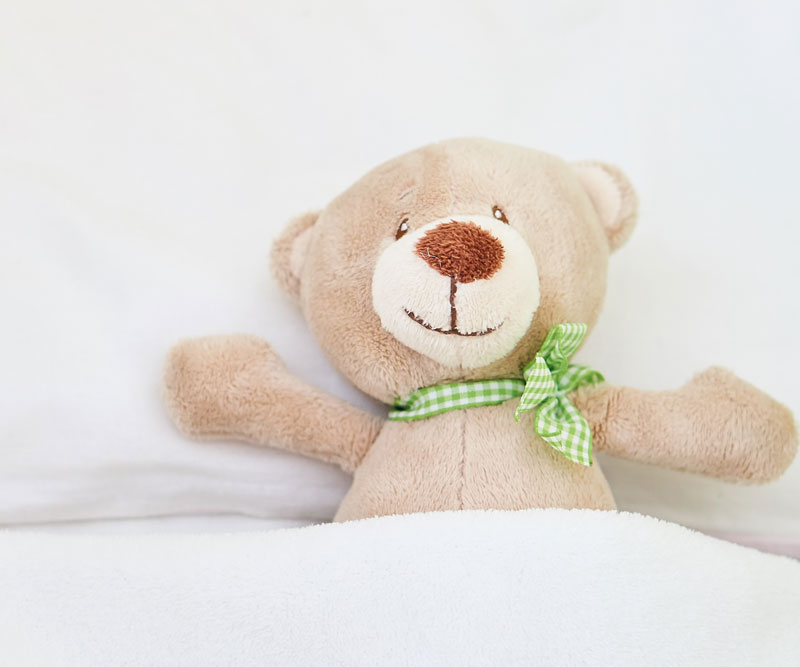 teddy bear tucked into bed