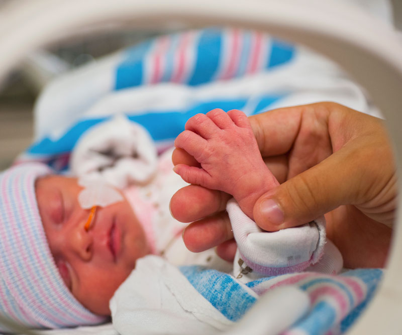 Woman holding her newborn baby's hand