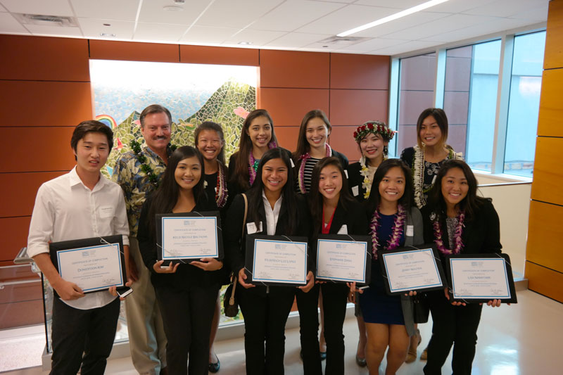 a group of interns holding up certificates from a summer internship