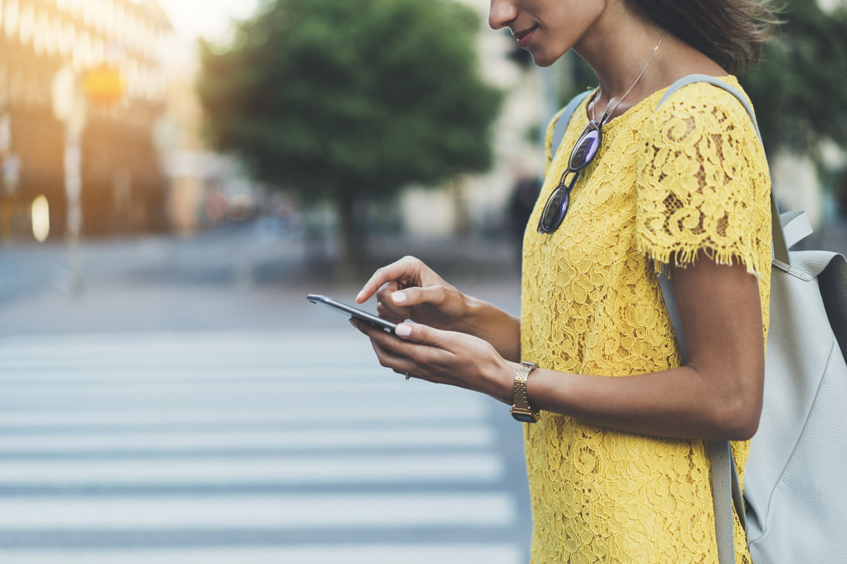 a women walking towards crossroads holding her mobile phone