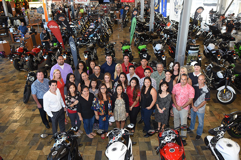 a group standing in a large garage surrounded by motorcycles looking down from above