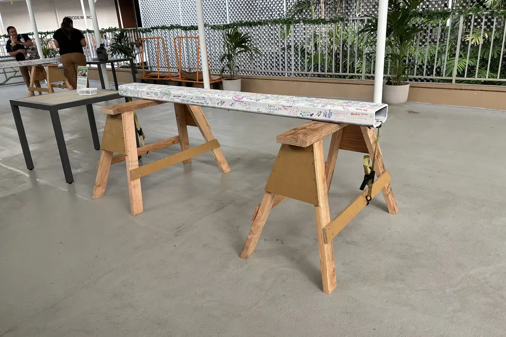 The white construction beam rests on wooden supports covered with signatures.