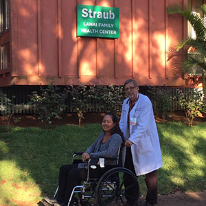 a patient in a wheelchair outside the hospital with a medical professional pushing her