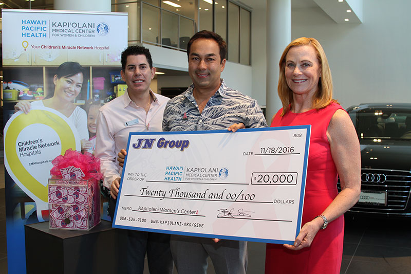 a group of people holding up a large check