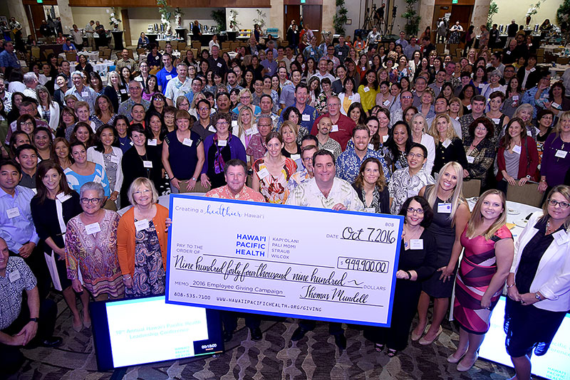 a very large group of people holding up a donation check