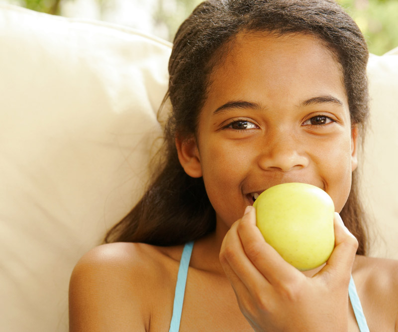 young girl taking a bite out of an apple