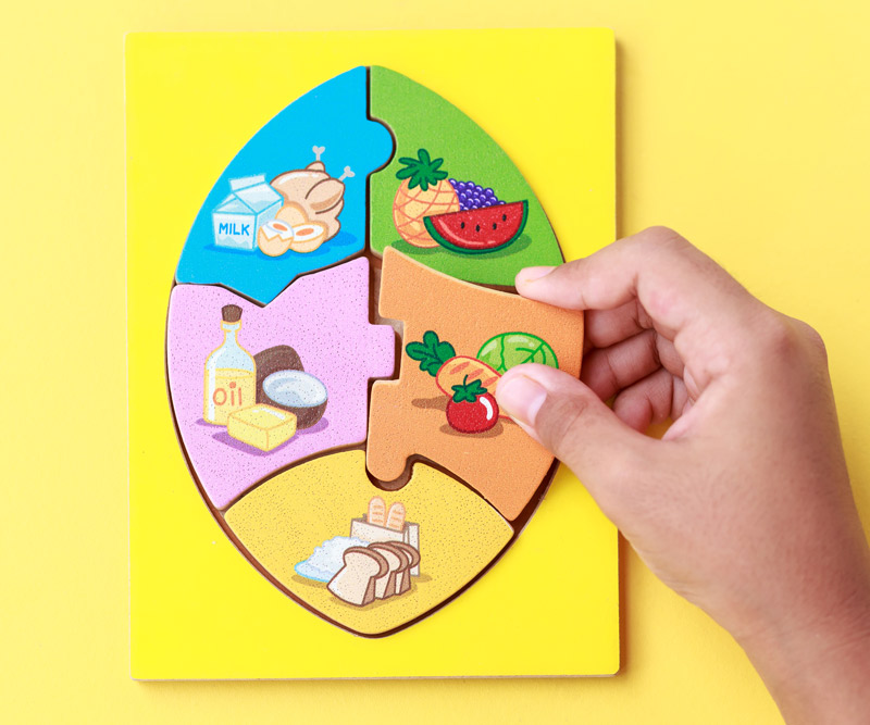 Child building a puzzle out of different food types