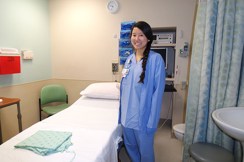 Photo of a hospital room with a professional next to a bed.