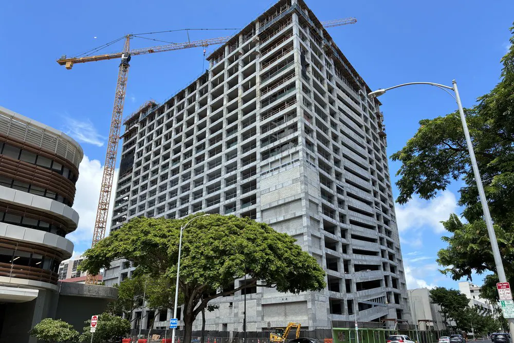 Street-level view of the parking building and crane under a clear blue sky.
