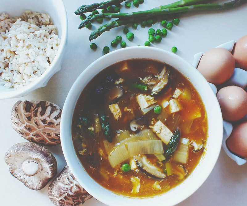 Springtime Egg Flower Soup in bowl surrounded by ingredients like mushrooms, eggs, rice, asparagus and peas