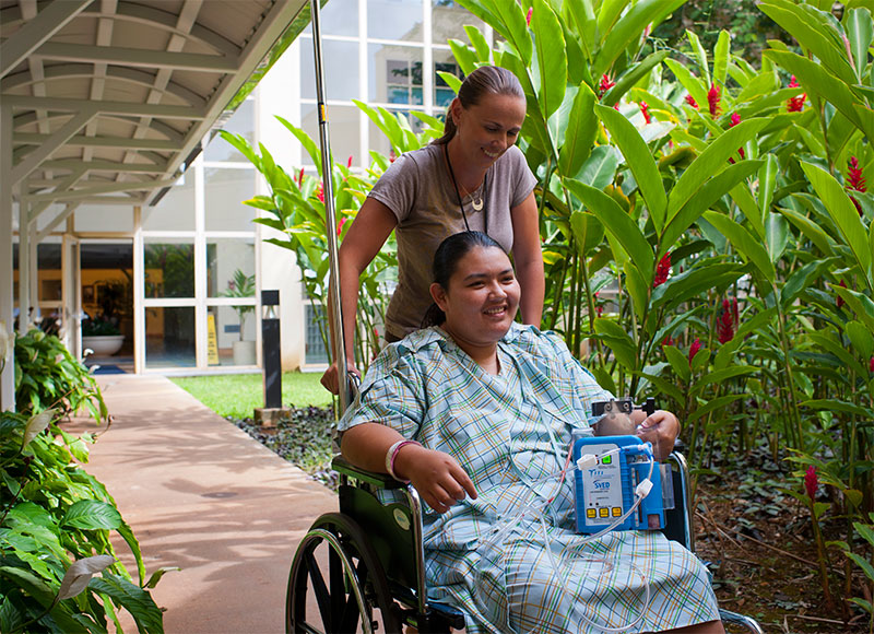 Photo of a patient in a wheelchair and health professional outside the hospital.