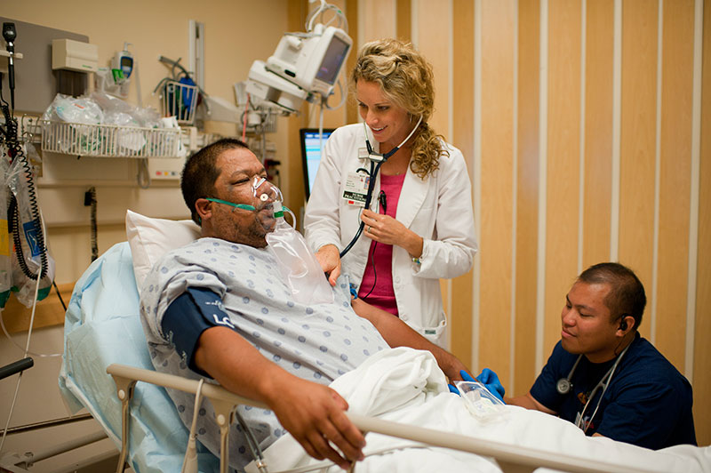 Health professionals taking care of a patient in a hospital bed.