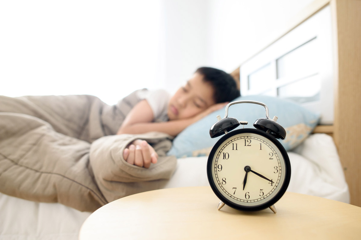 child sleeping near alarm clock