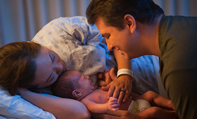 Parents embracing their newborn baby