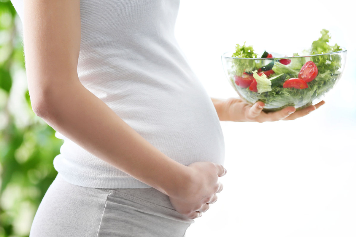 Pregnant woman holding a bowl of salad