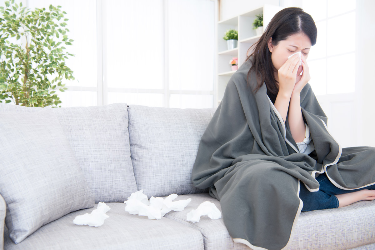 woman with a cold sits on her couch