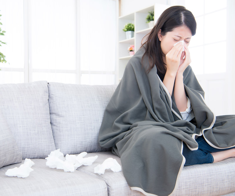 woman with a cold sits on her couch