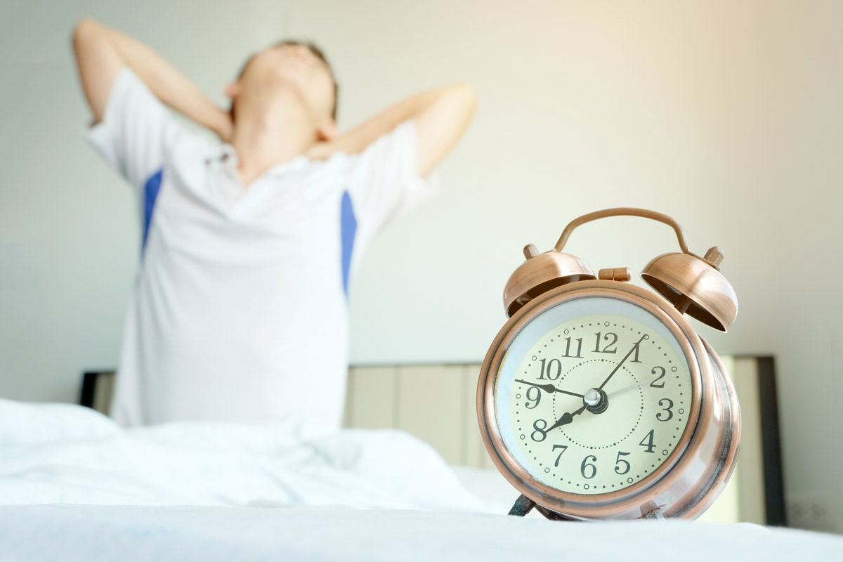 boy rising out of bed and clutching sore neck