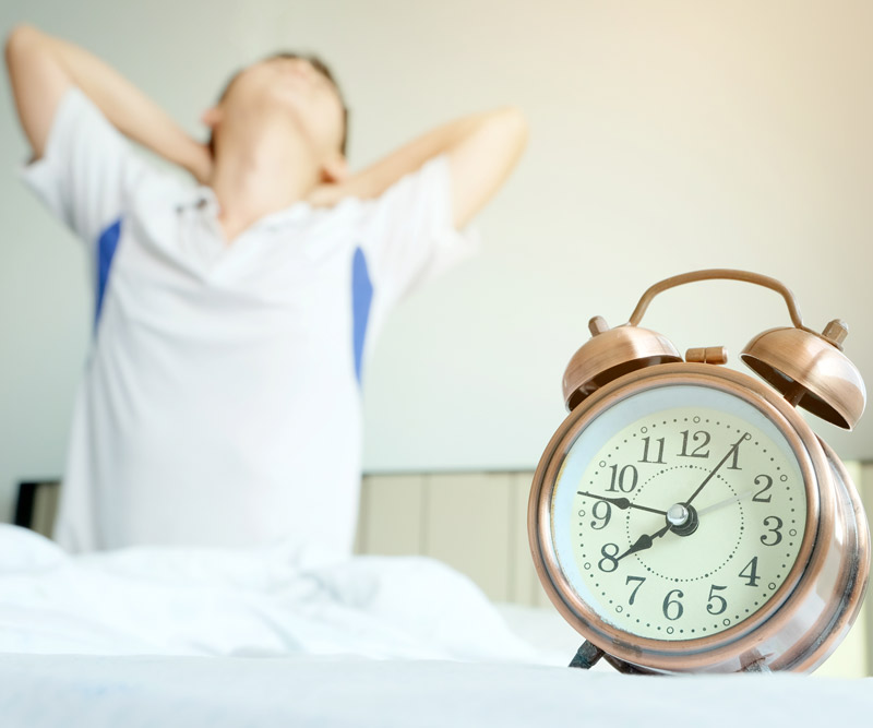 boy rising out of bed and clutching sore neck