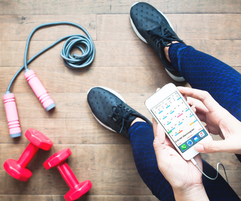 person using phone sitting next to workout equipment