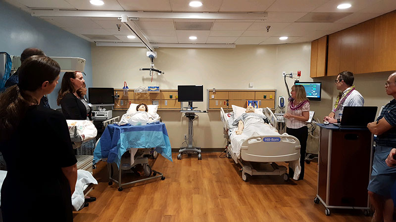 Group of people in hospital room with simulation mannequins lying in two beds