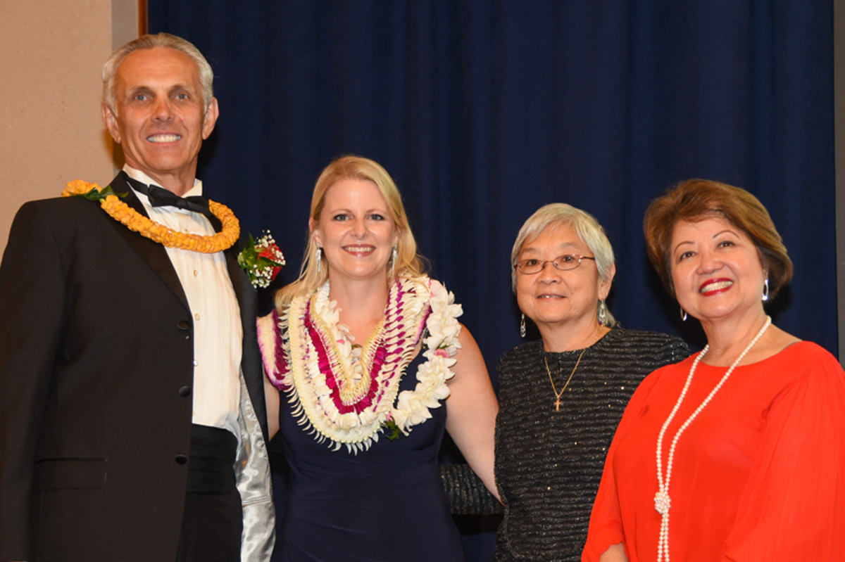 A man and three women stand on stage during a ceremony.