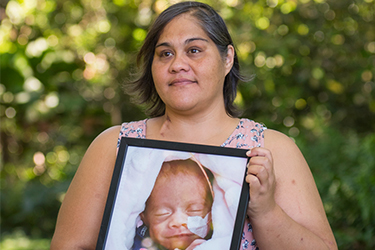 Women holding framed photo of a young baby