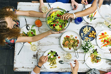 People sitting at a table, eating salad