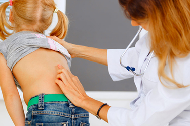 Young child getting her spine examined from doctor