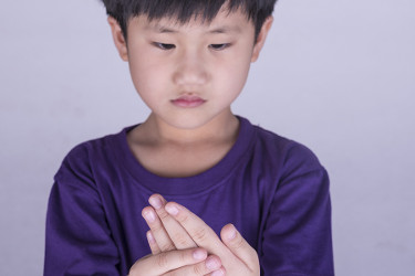 Young boy clutching his hand