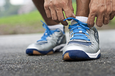 a close up of a runner adjusting their shoes