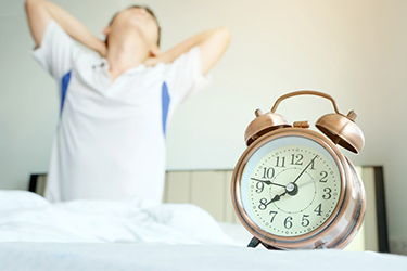 boy rising out of bed and clutching sore neck