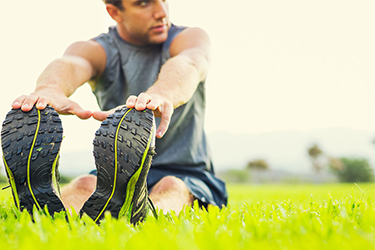 man sitting in the grass stretching