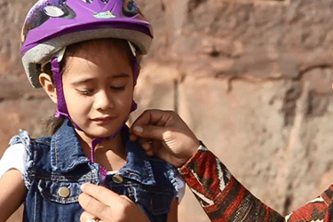 Mother fastening a helmet on her child