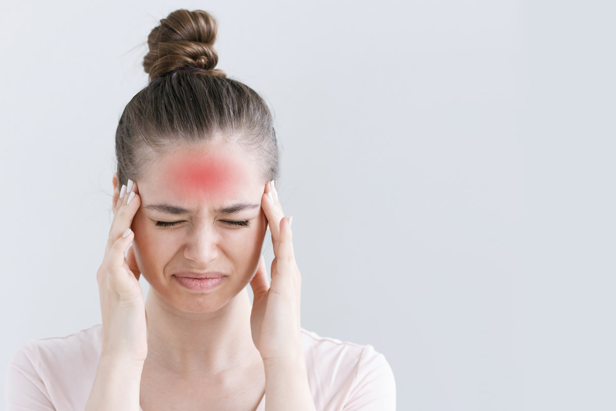 Woman with a headache holds her head in pain