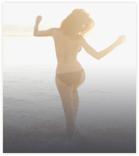 Woman dancing at the beach wearing a black bikini
