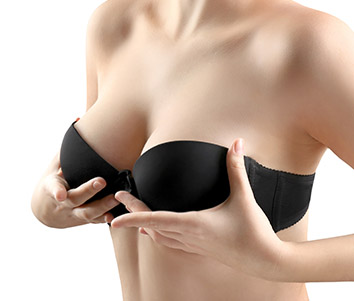 Torso of a naked women wearing a black bra lifting up her breasts with her hands